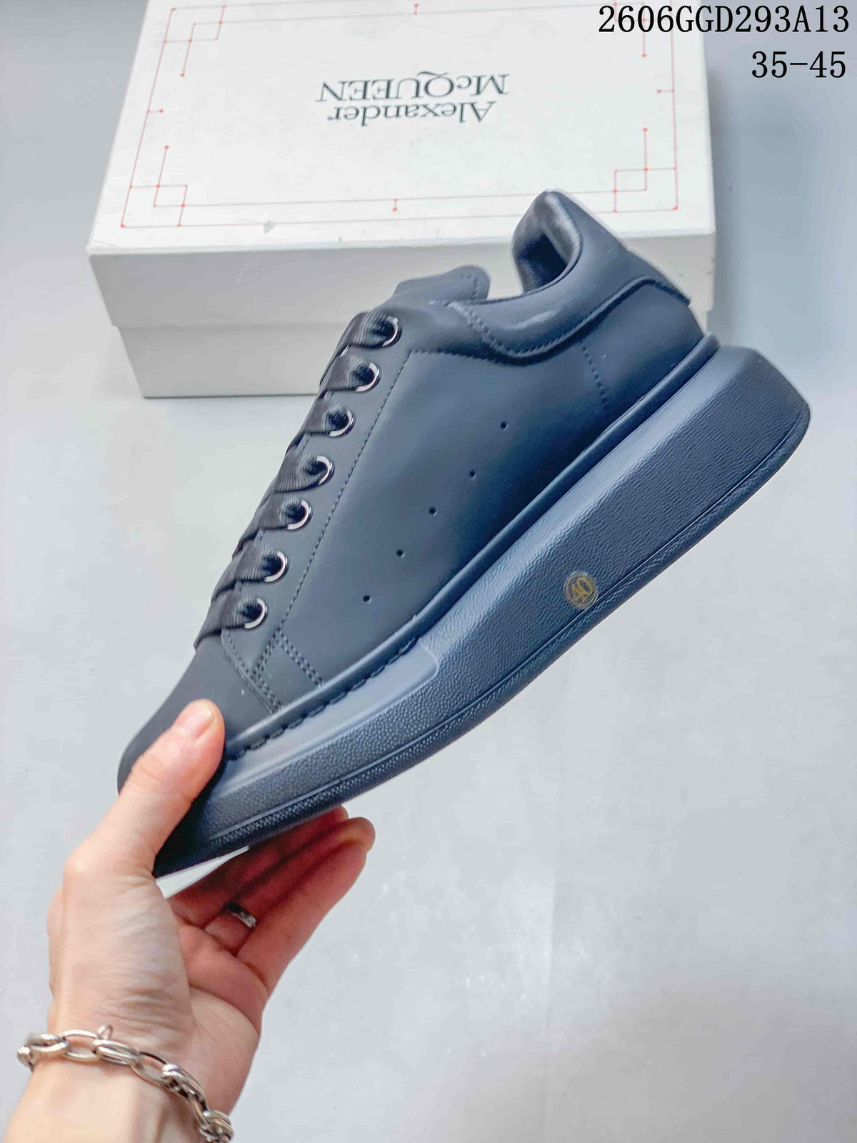 Side view of a dark charcoal low-top sneaker with subtle perforations and a chunky sole.