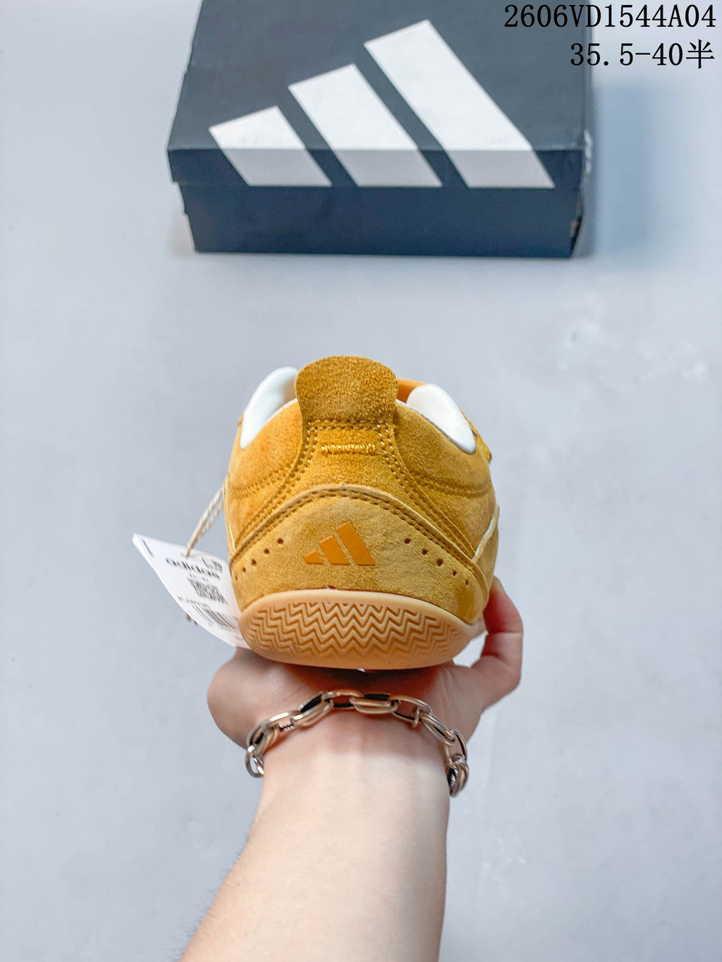 Rear view of a golden yellow low-top sneaker with heel branding and patterned outsole.
