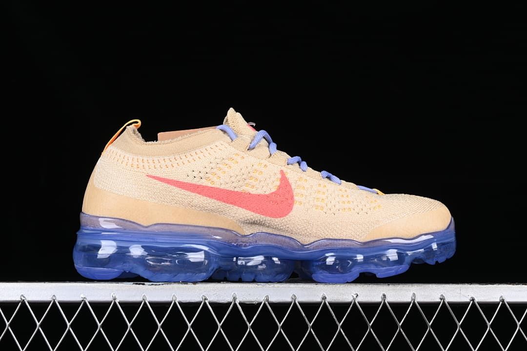 Side profile of the beige knit sneaker with coral-pink Swoosh and translucent blue sole.