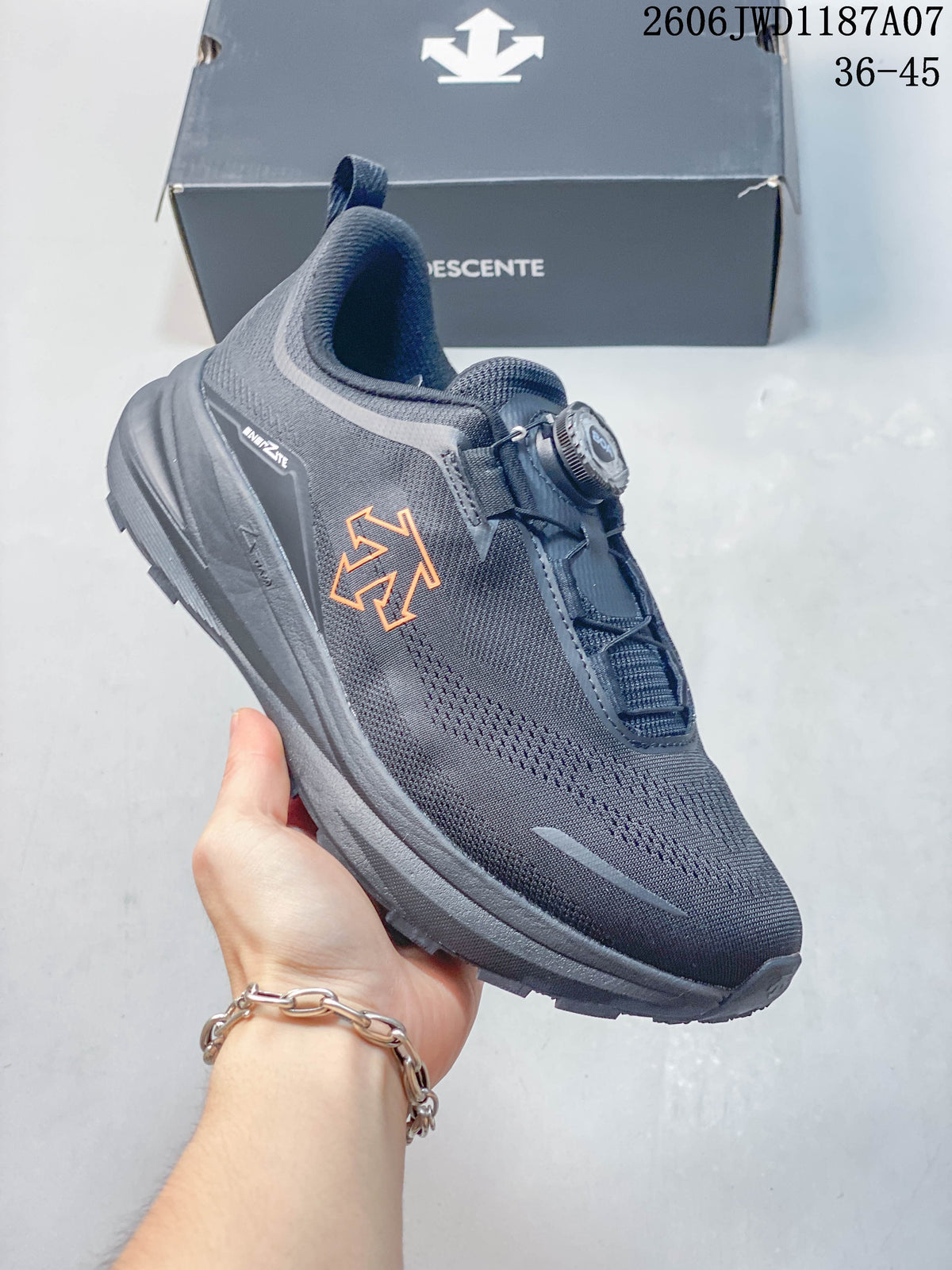 Angled side view of a dark gray DESCENTE sneaker with orange side detailing and dial closure.