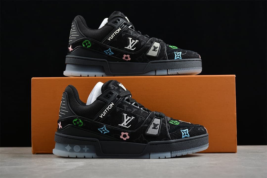 Two black low-top sneakers displayed on and in front of an orange box