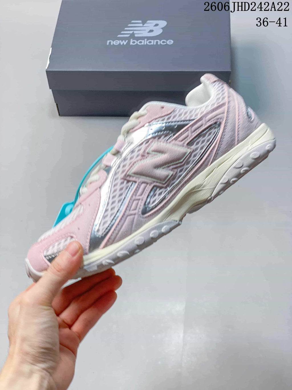 Side view of a pink and silver New Balance sneaker with mesh panels.