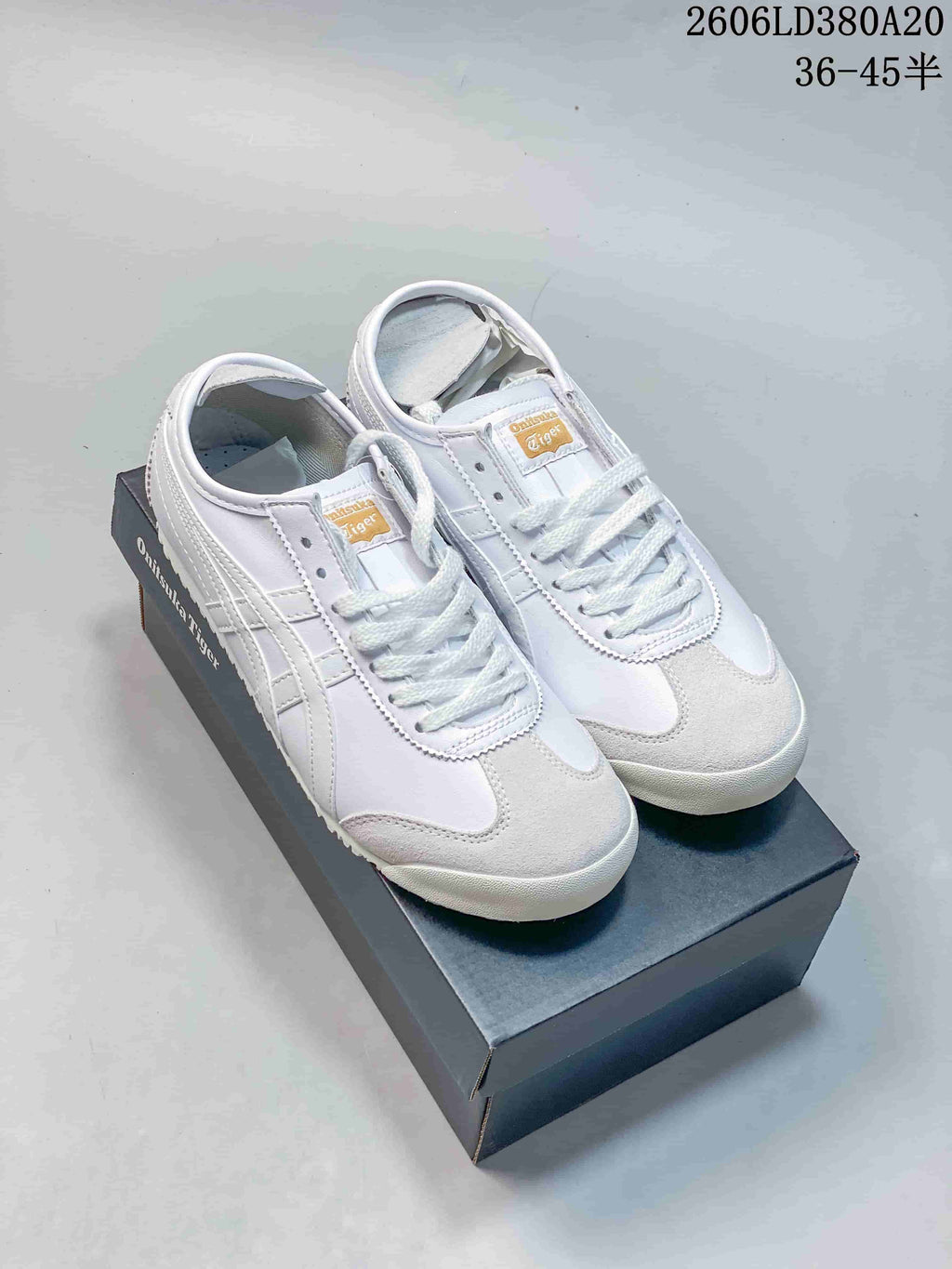 Pair of white Onitsuka Tiger Mexico 66 low-top sneakers with light gray accents on a shoebox