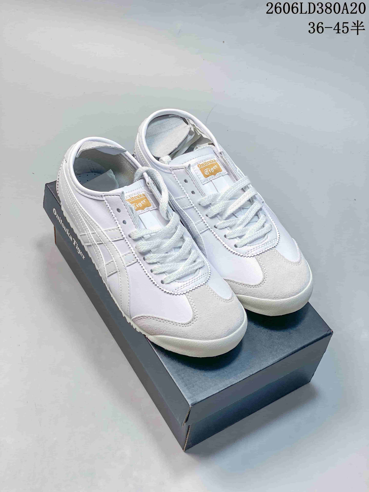 Pair of white Onitsuka Tiger Mexico 66 low-top sneakers with light gray accents on a shoebox