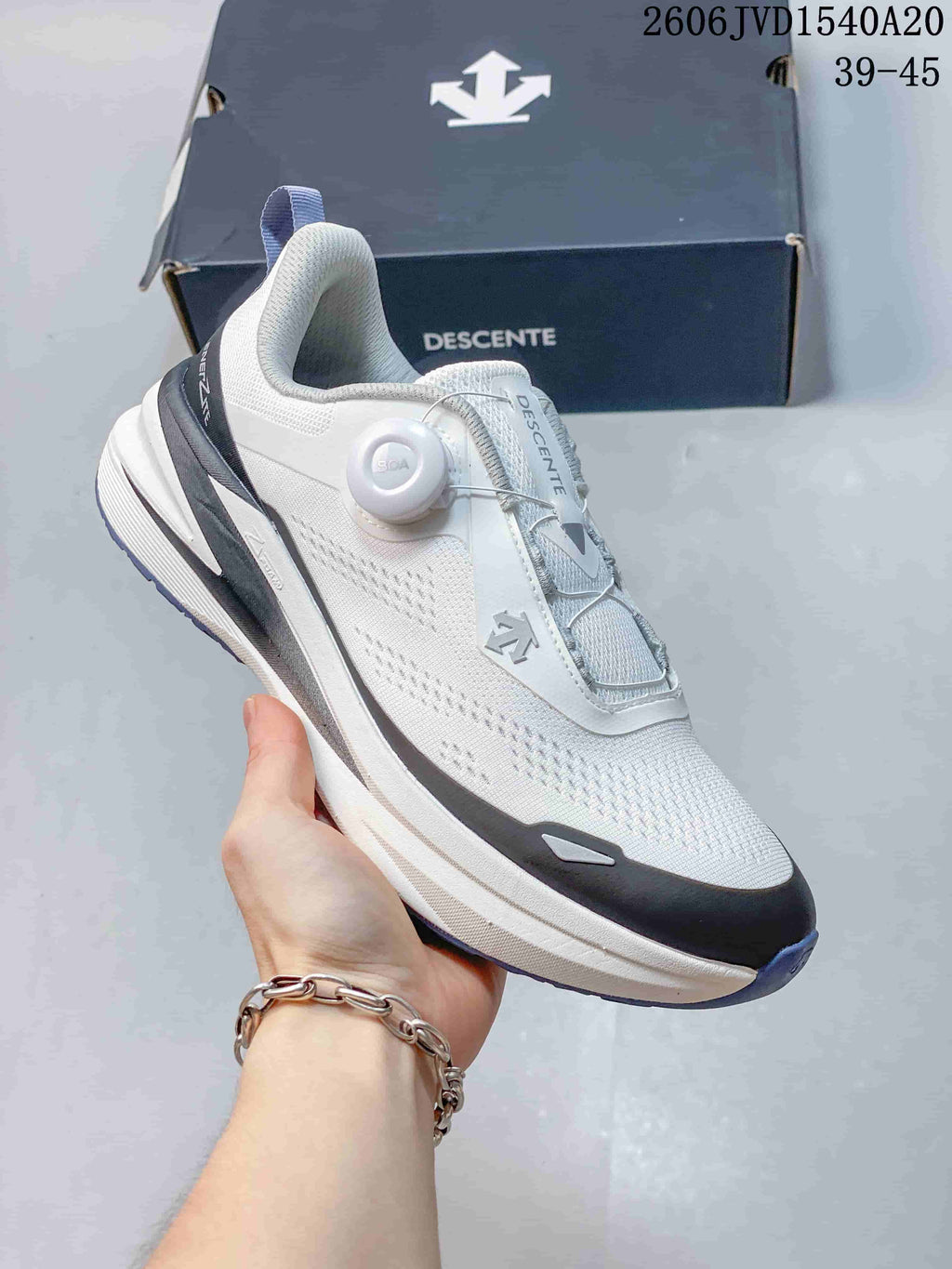 Angled side view of a white and gray DESCENTE sneaker with dial-style closure