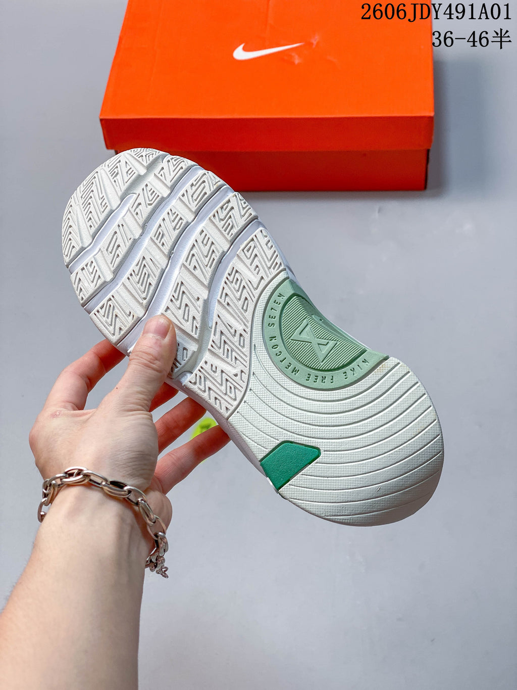 Underside of a white training shoe showing its patterned outsole and green accents.
