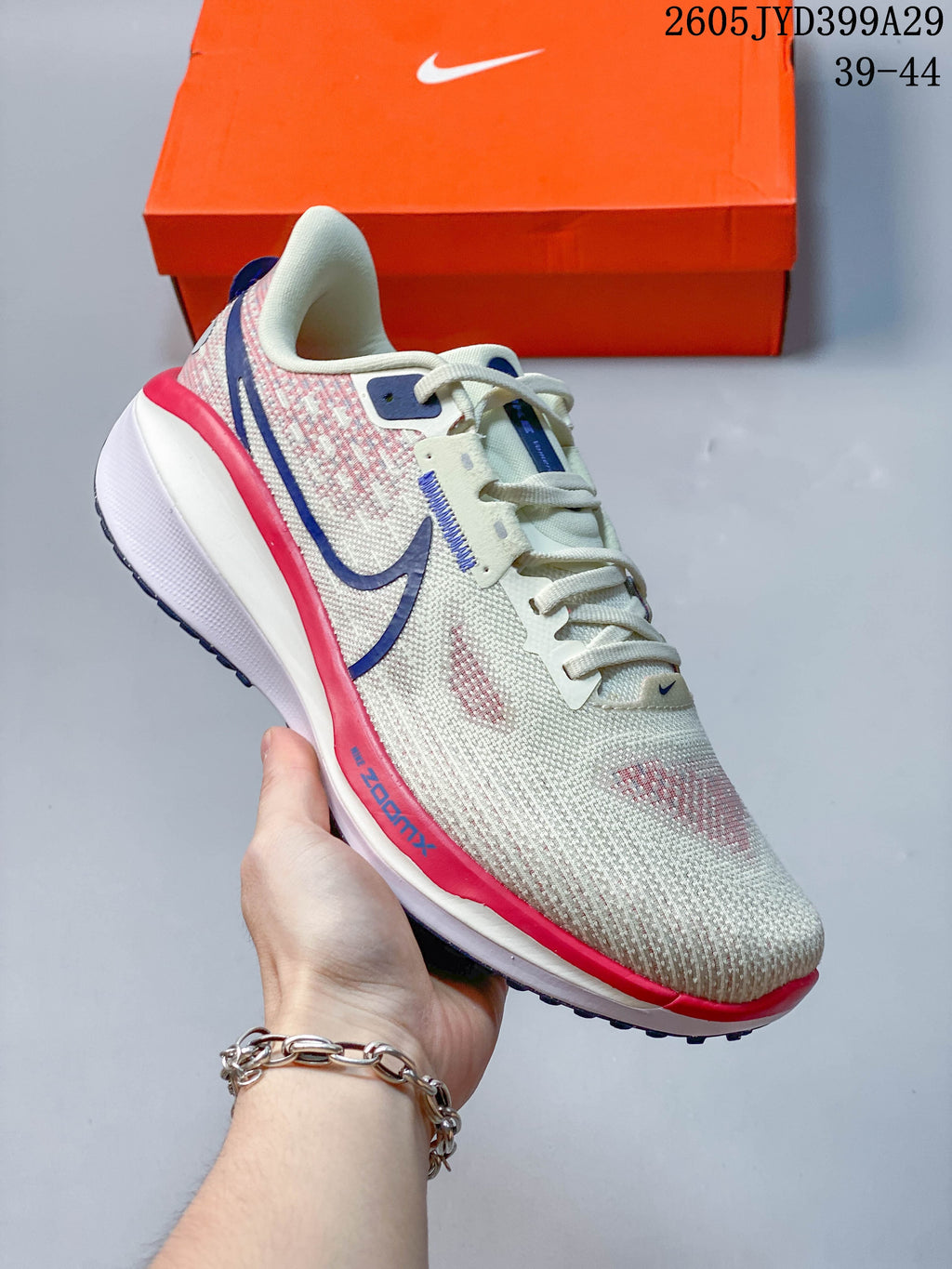 Off-white Nike Air Zoom Vomero 17 running shoe with pink and blue accents.