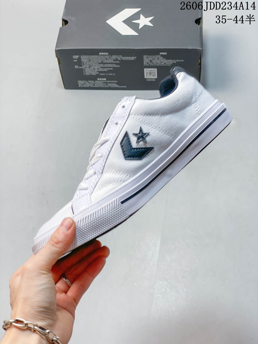 Side view of a white low-top sneaker with a navy star-chevron emblem