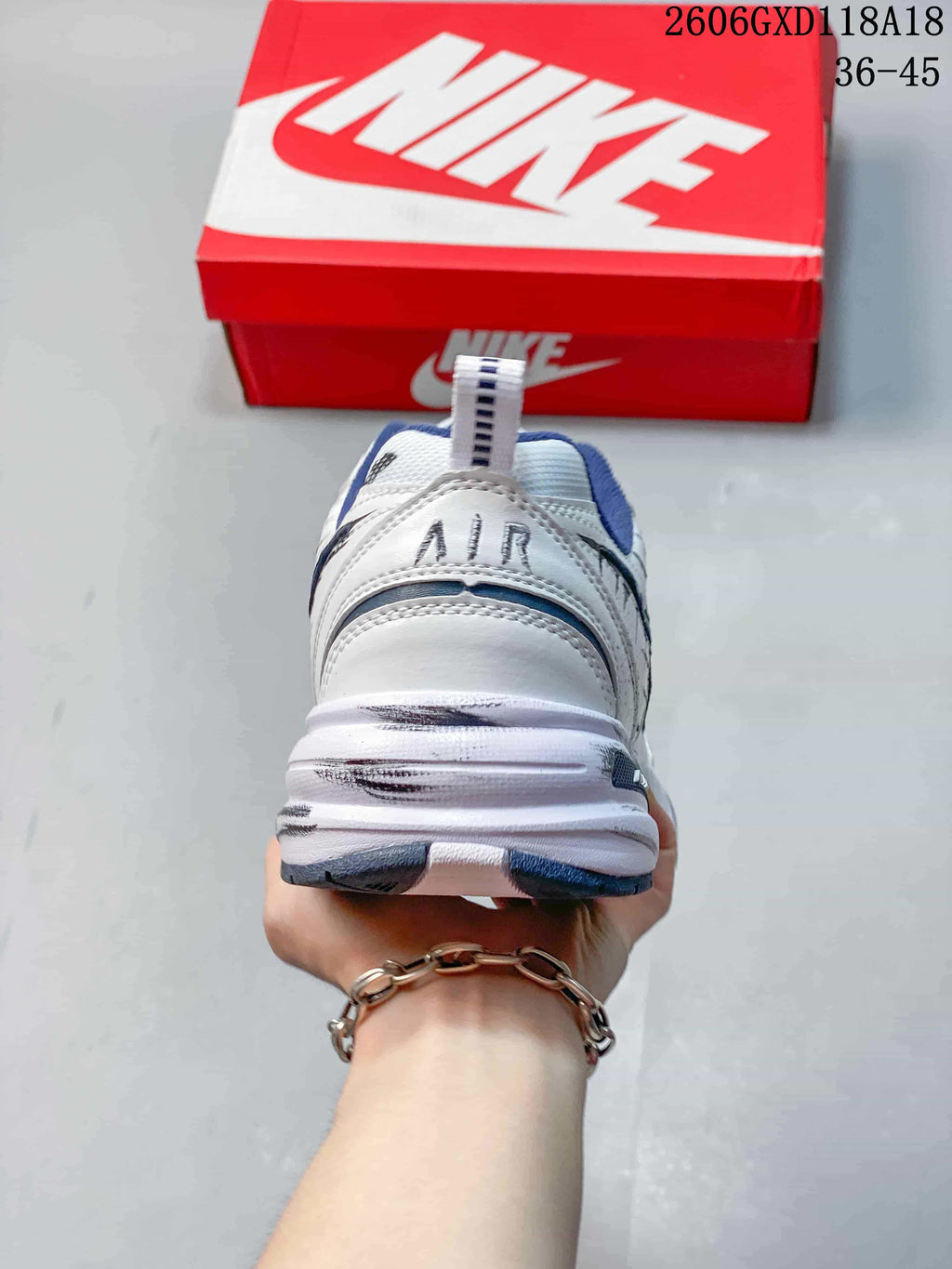 Rear view of a white Nike Air Monarch sneaker with navy accents and a chunky sole.