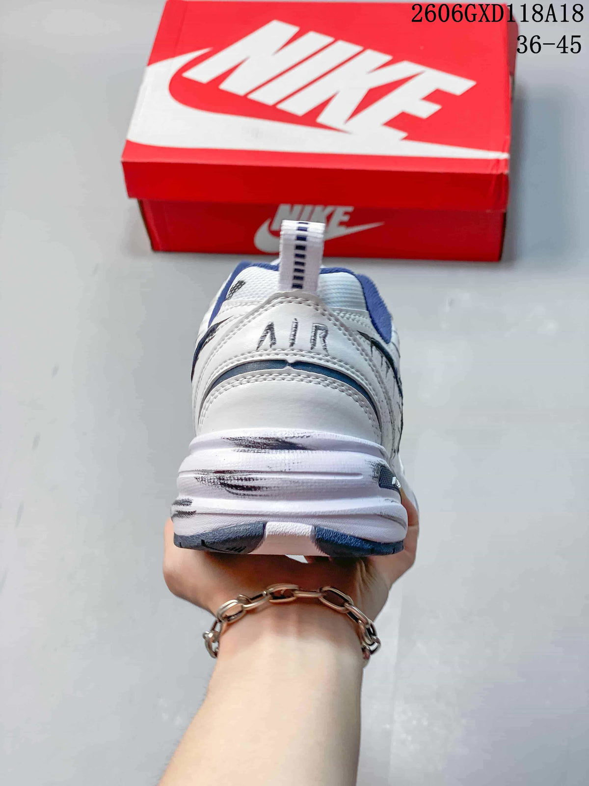 Rear view of a white Nike Air Monarch sneaker with navy accents and a chunky sole.