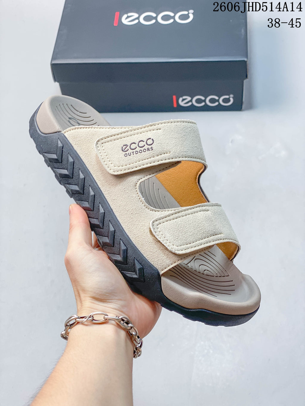 Side view of a cream-colored two-strap sandal with a contoured footbed and dark outsole.