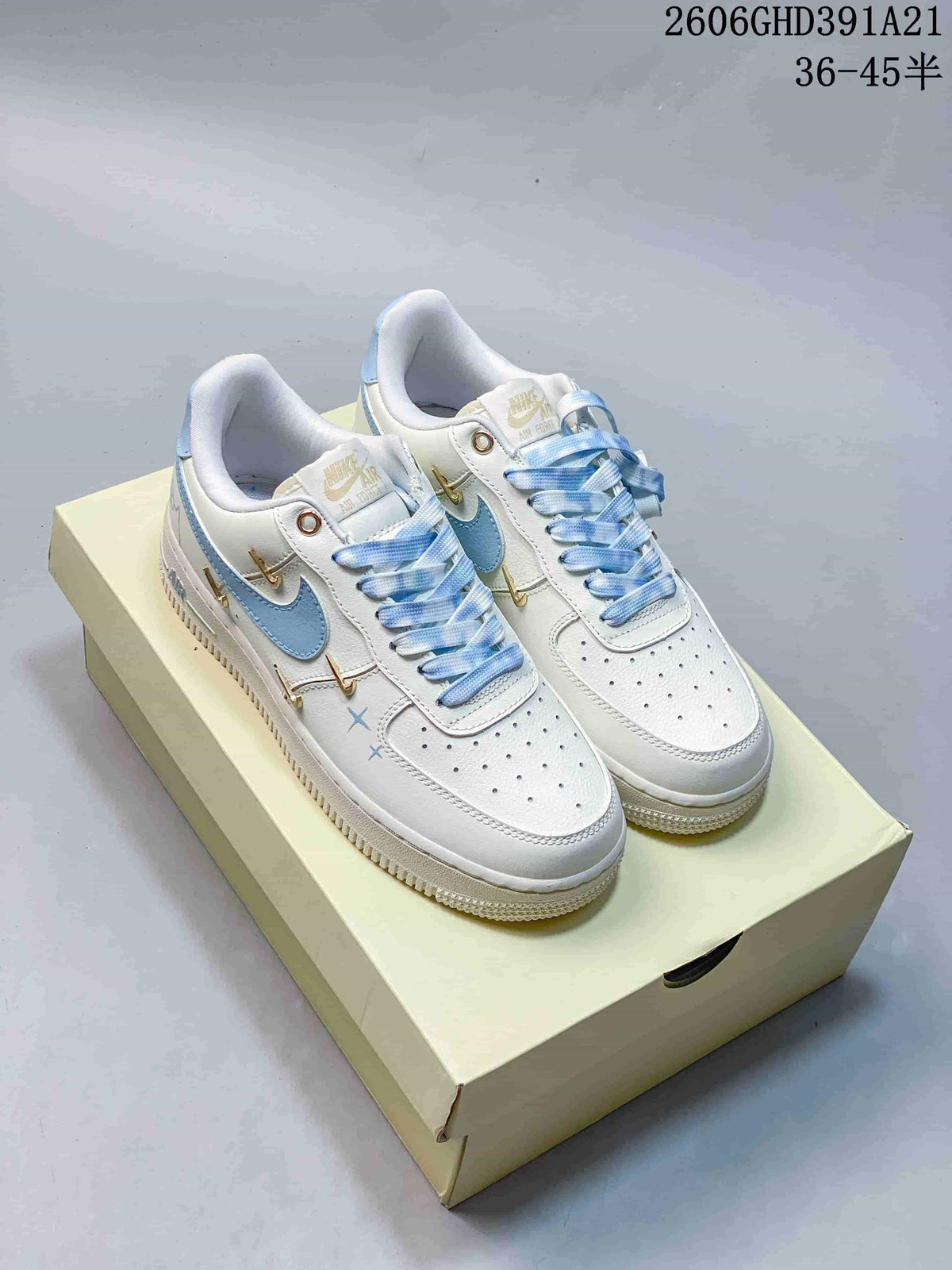 Pair of white low-top sneakers with light-blue Swoosh accents, patterned laces and gold-tone details.