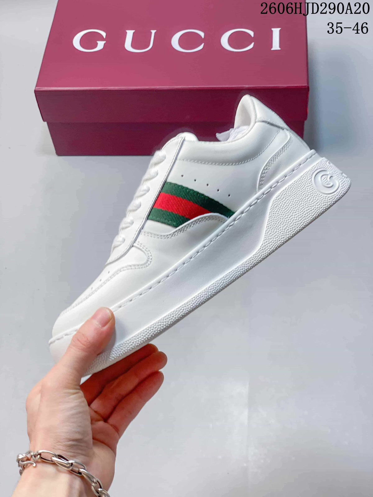 Side view of the white sneaker with green-and-red stripe detail