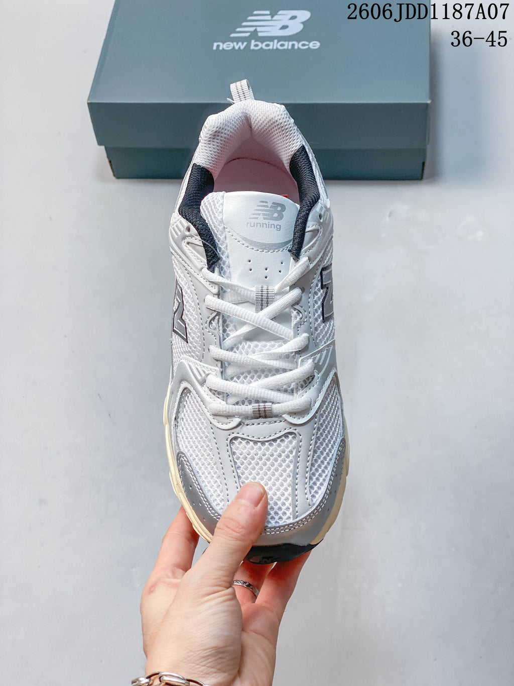 Top view of the laces and mesh-look panels on a white and grey New Balance 530 sneaker