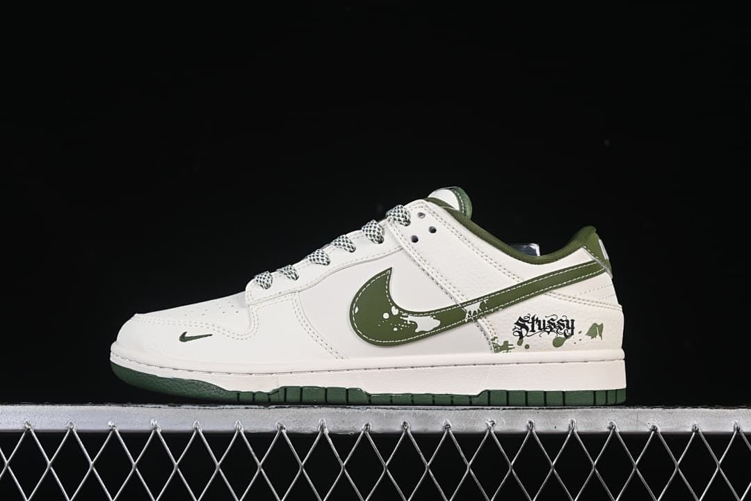 Side view of a white and dark green low-top sneaker with splatter-style swoosh and heel graphics.