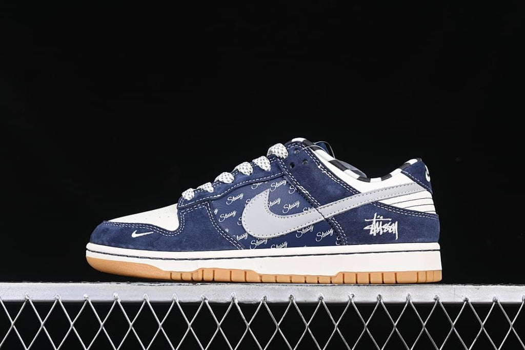 Side view of navy and grey low-top Dunk sneakers with script graphics and a gum-colored outsole