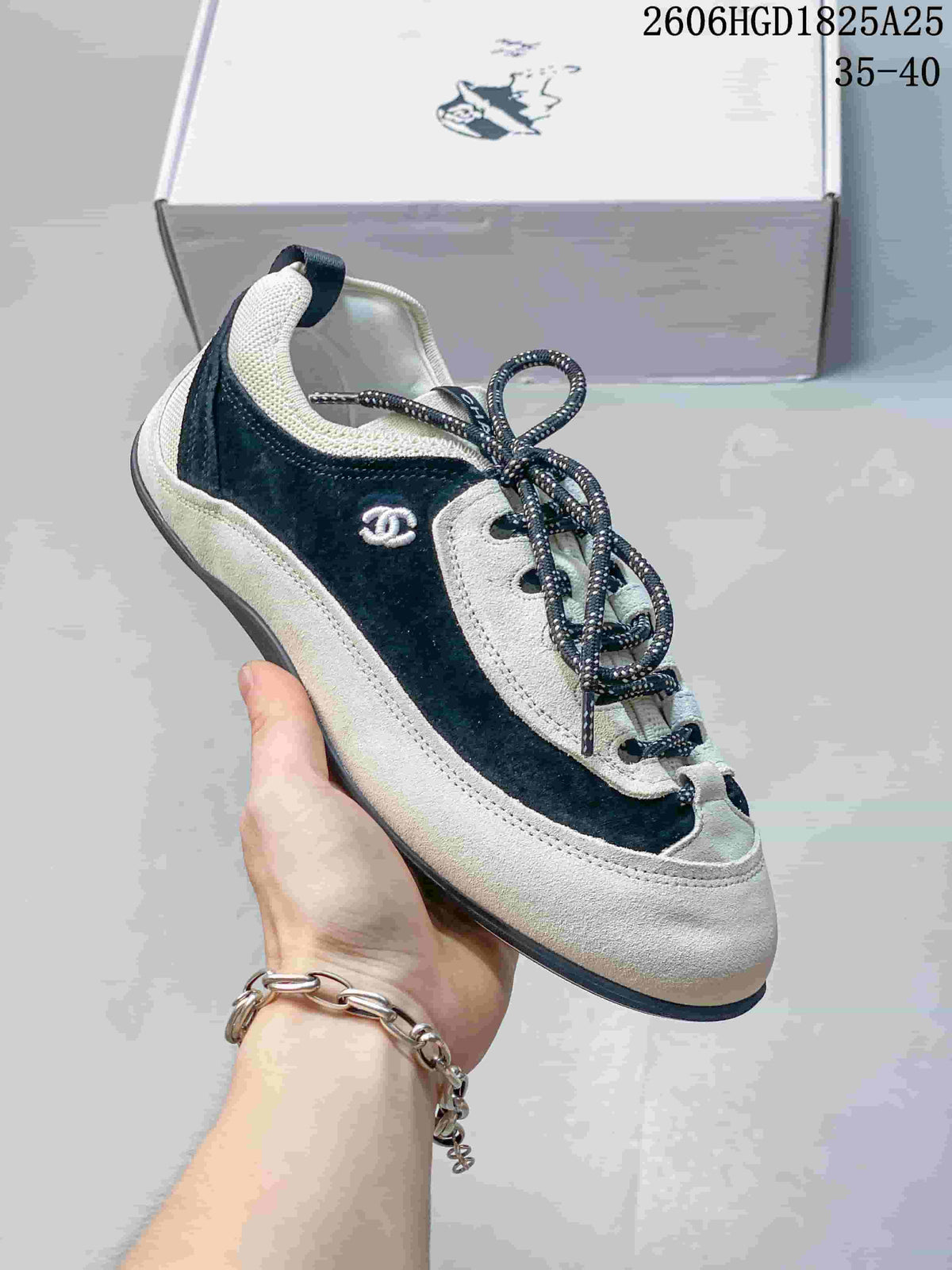 Side view of a black and ivory low-top trainer with a small side emblem and speckled laces.