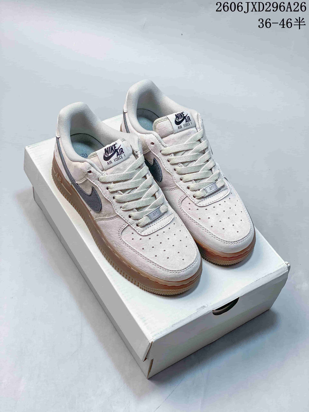Light gray Nike Air Force 1 low-top sneakers with dark Swooshes and tan-toned outsoles