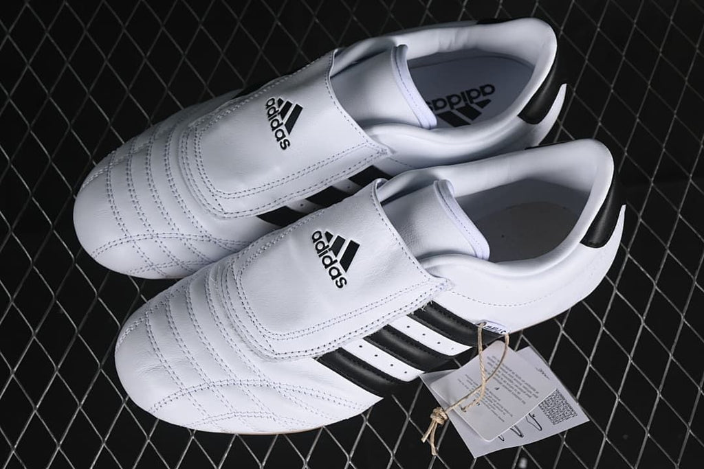 Pair of white and black adidas Taekwondo shoes viewed from above.