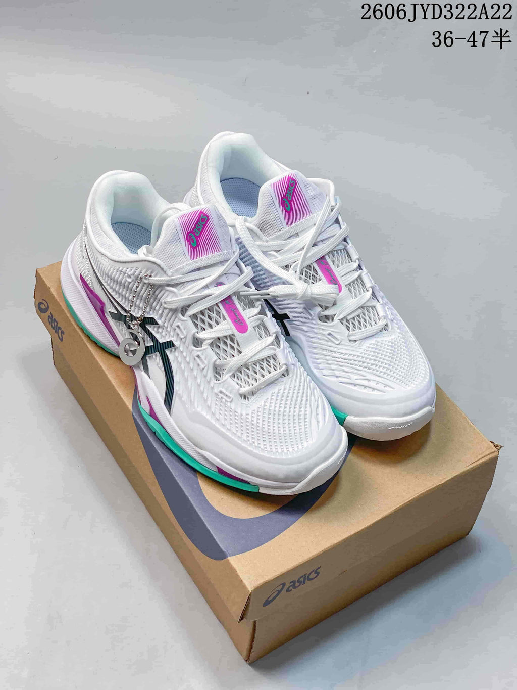 Pair of white ASICS Resolution Speed FF 4 tennis shoes with teal and magenta accents on a shoebox.
