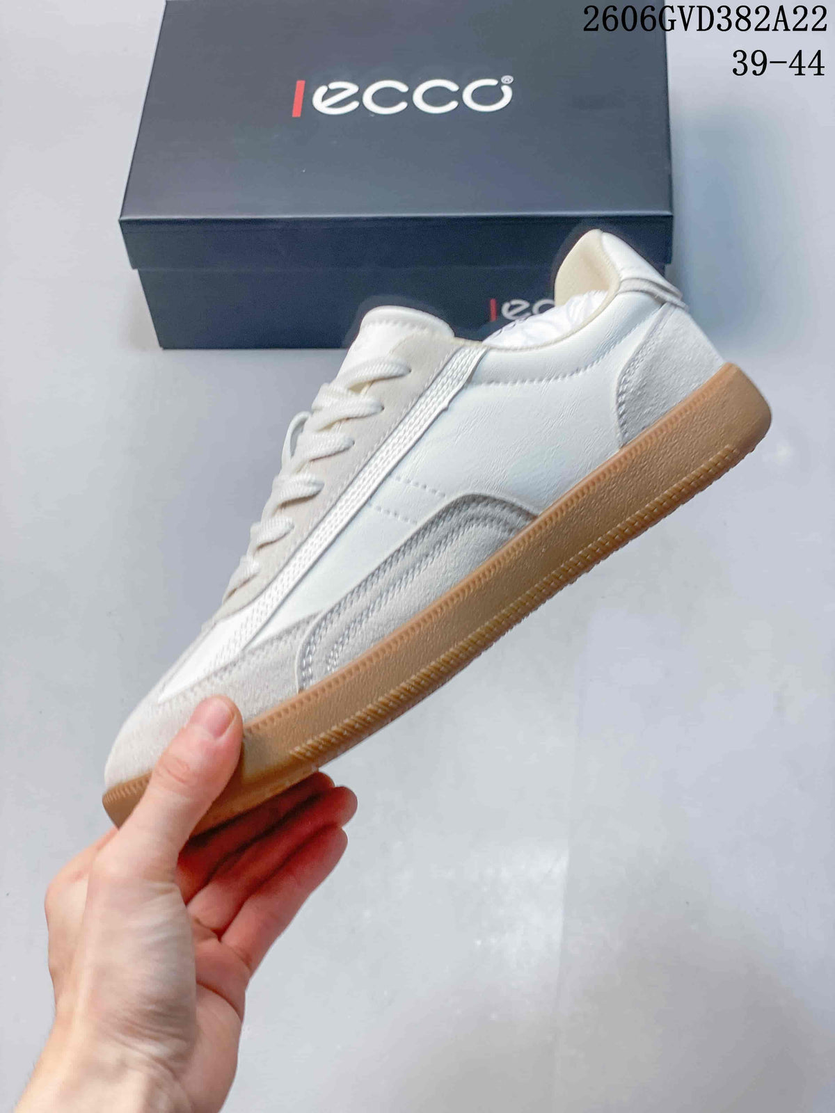 Side view of a light-colored low-profile sneaker with textured panels and a gum sole