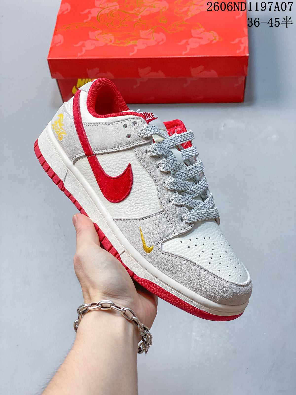 Close view of a white and light gray low-top sneaker with a red Swoosh, red lining, and small yellow accent.