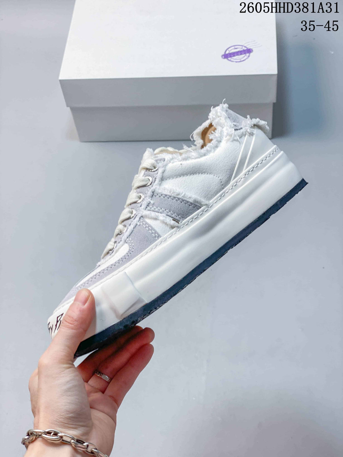 Side view highlighting the layered panels and thick sole of a white and gray low-top sneaker