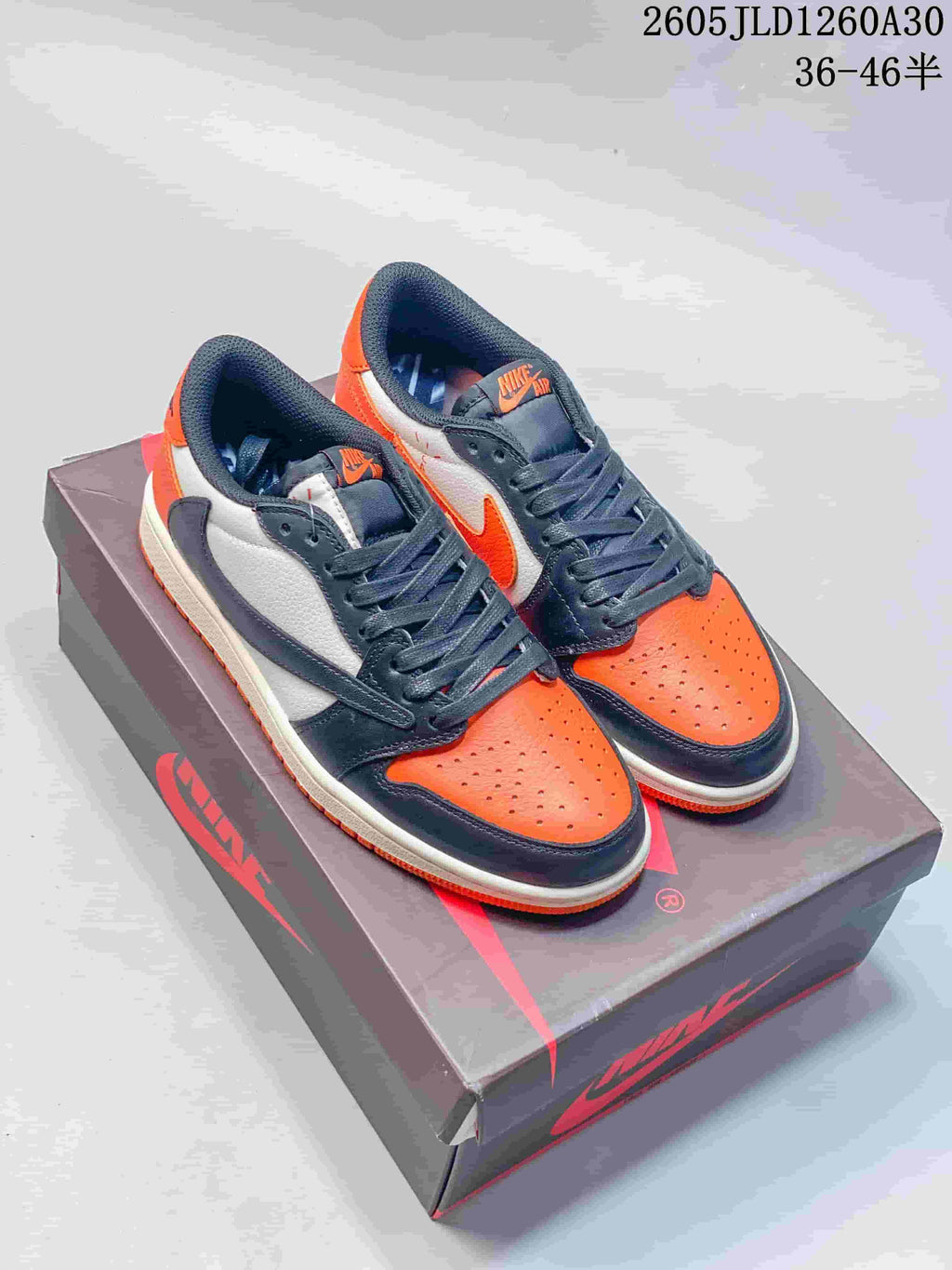 Pair of orange, white, and charcoal Jordan Air Jordan 1 Low sneakers on a shoebox