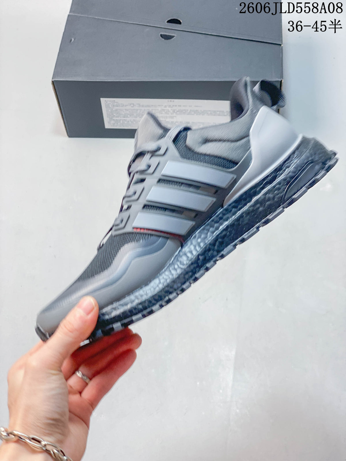 Side profile of a grey adidas UltraBOOST-style sneaker with red accents and a rugged outsole.