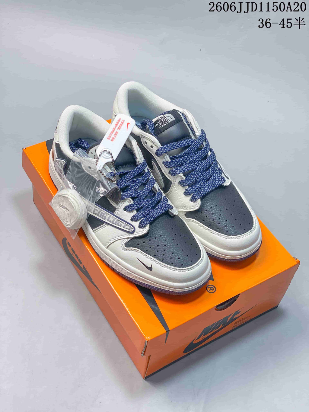 Navy and white low-top sneakers with blue patterned laces on an orange box.