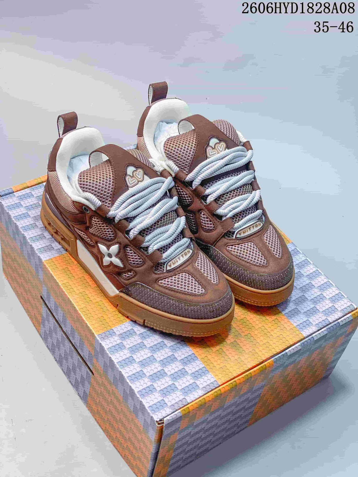 Pair of brown Louis Vuitton Trainer sneakers with white laces and gum-colored soles on a patterned box