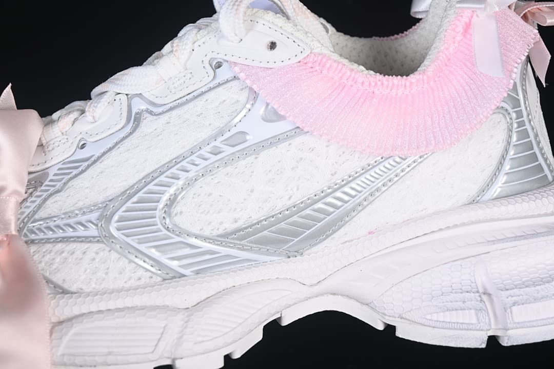 Close-up of the white and silver-toned side panels and pink collar trim.