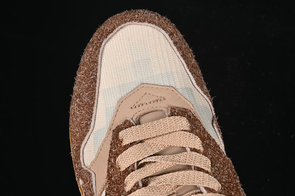 Top-down close-up of the cream toe panel, brown overlays, and tan laces.