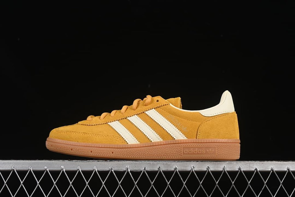 Side profile of a golden-yellow adidas Handball Spezial sneaker with cream stripes and a gum-colored sole