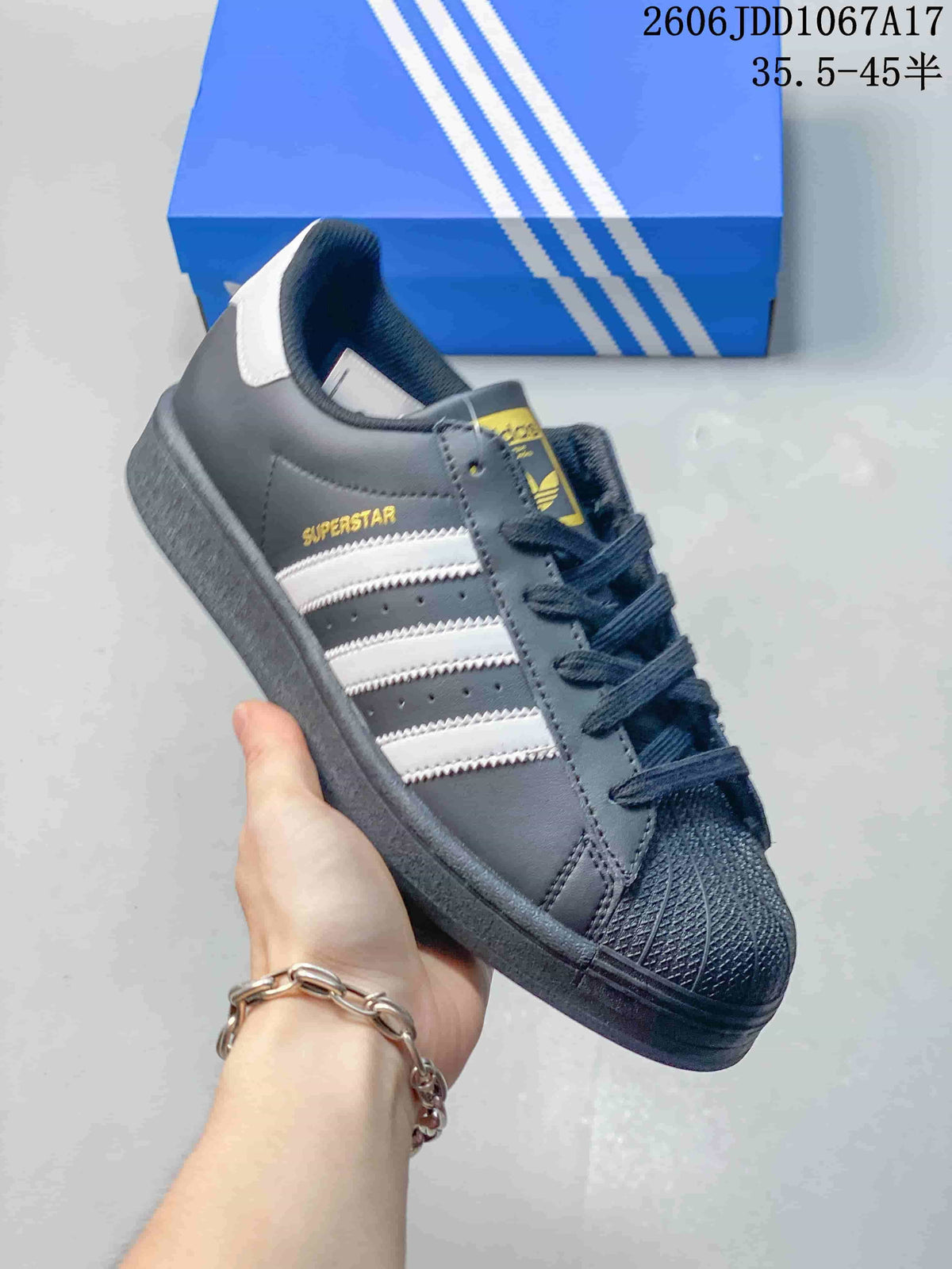 Dark gray Adidas Superstar sneaker with white stripes and a textured shell toe.