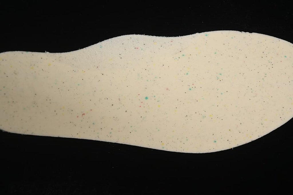 Close-up of a light-colored shoe insert with small multicolored speckles.