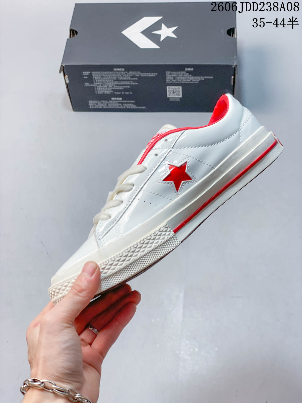 Side view of a white low-top sneaker with a red star and red sole stripe