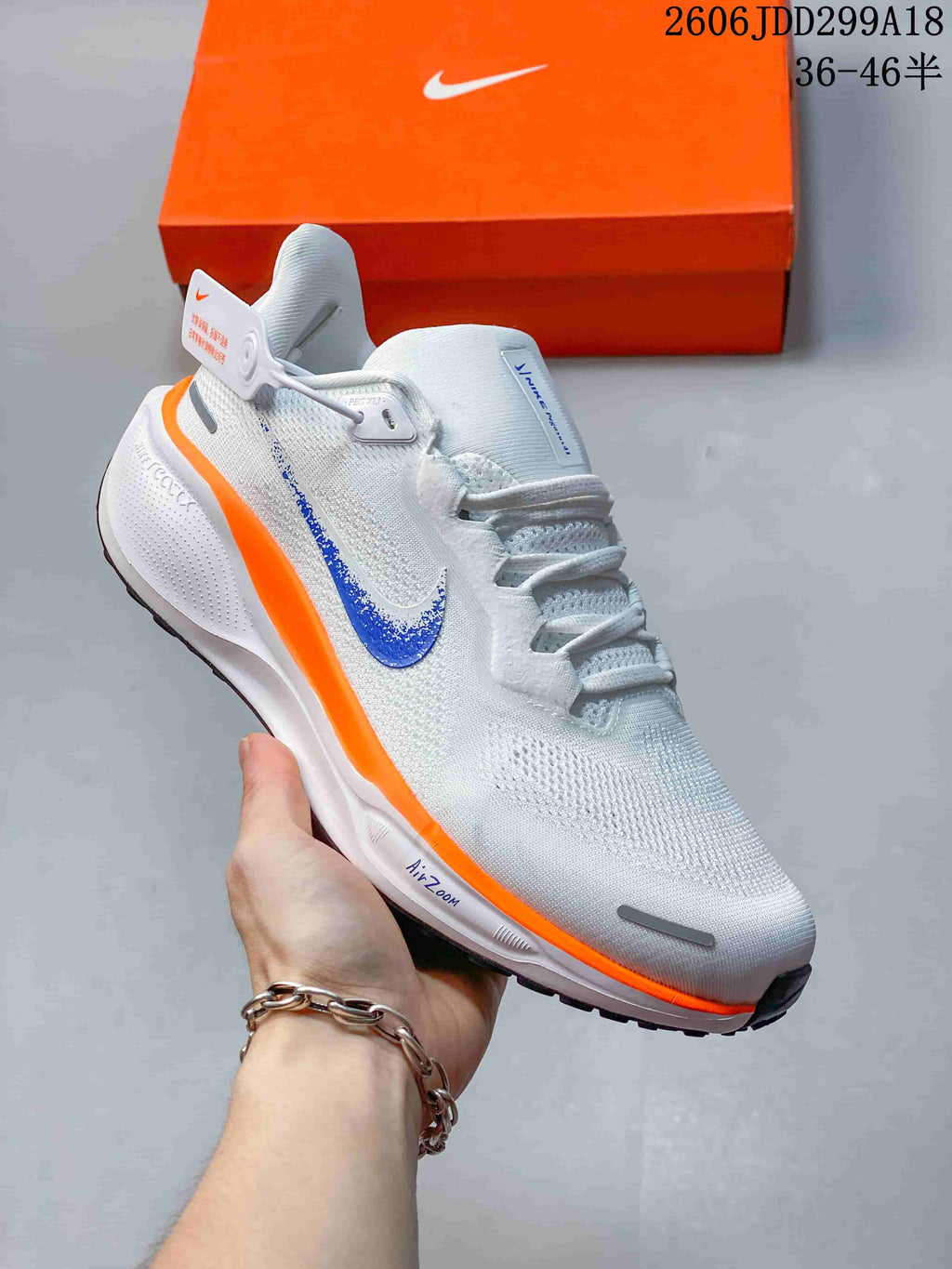 Side view of a white Nike running shoe with a blue Swoosh and bright orange midsole stripe