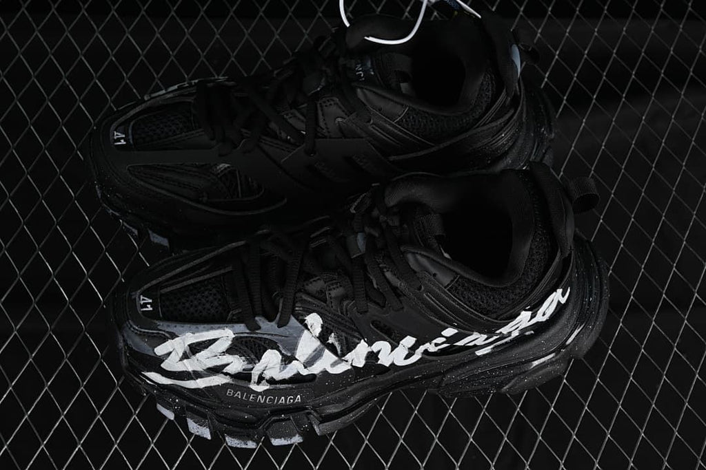 Pair of black Track sneakers with contrasting white graphics.