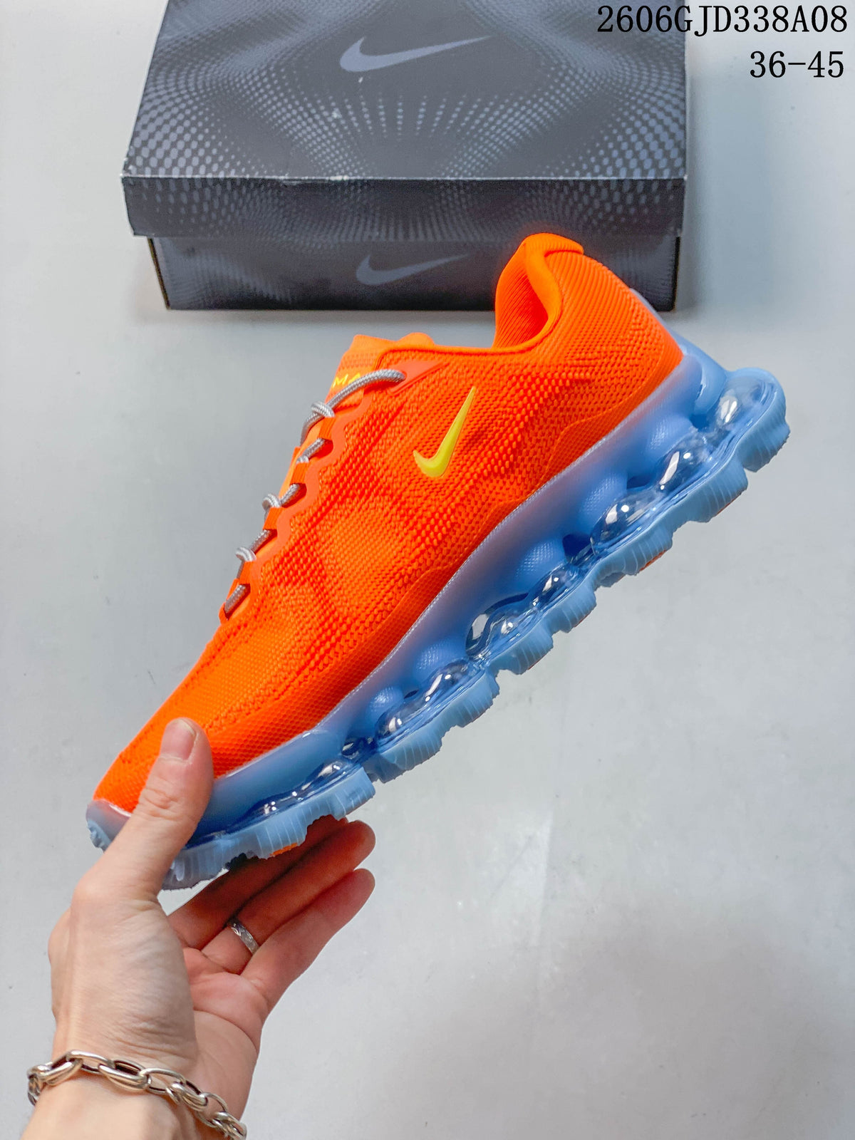 Side view highlighting the orange upper, yellow logo, and segmented blue sole.