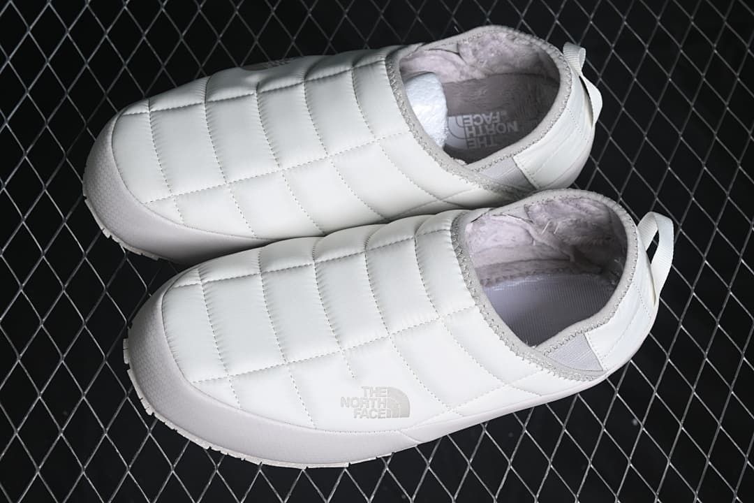Pair of white quilted mule slippers viewed from above.