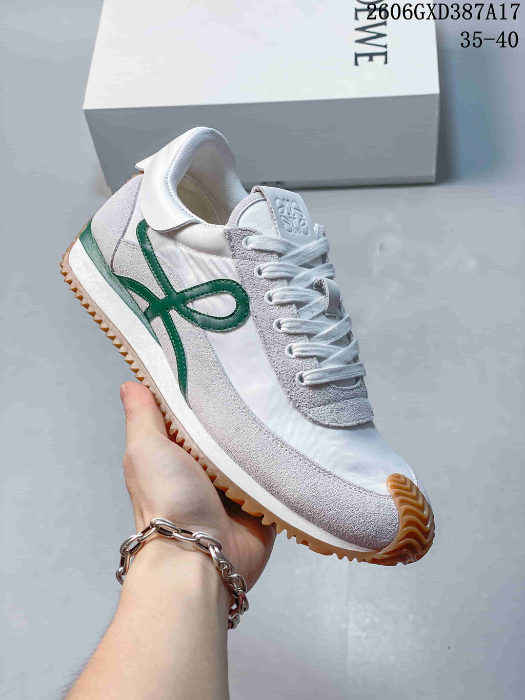 Angled side view of the white sneaker with green accents and gum-colored outsole