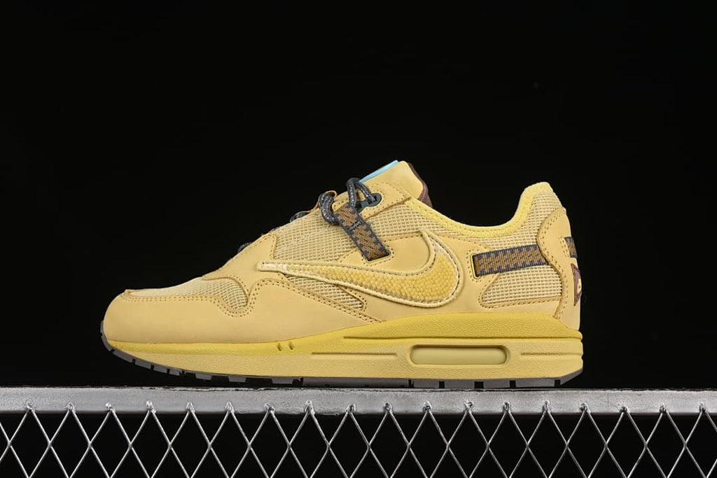 Side profile of a wheat-colored Nike Air Max 1 sneaker against a dark background.