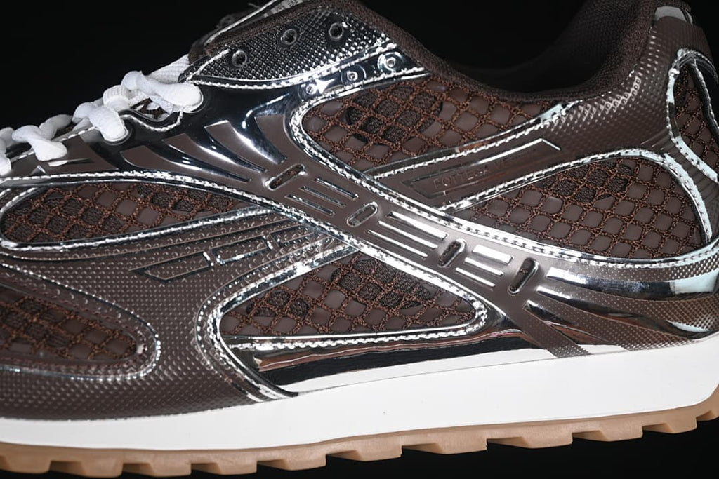 Close-up of the sneaker's brown mesh-patterned upper and reflective silver-tone overlays.