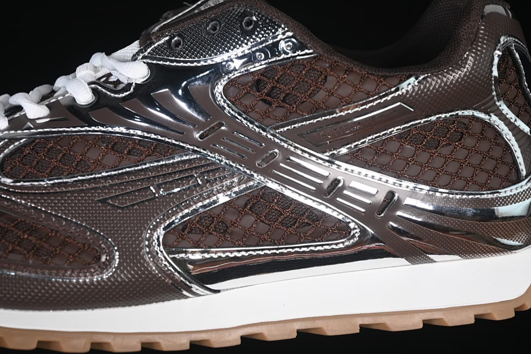 Close-up of the sneaker's brown mesh-patterned upper and reflective silver-tone overlays.