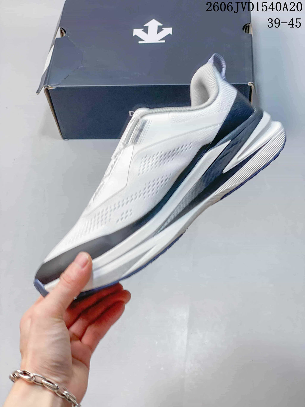Side profile of a white and gray DESCENTE sneaker with navy-toned heel detailing