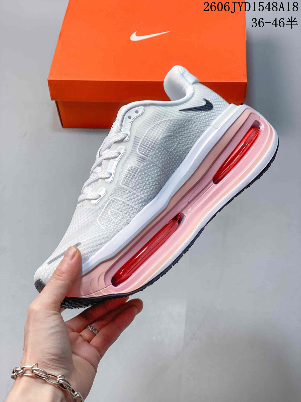 Side view of a white running shoe with pink midsole accents and visible cushioning windows.