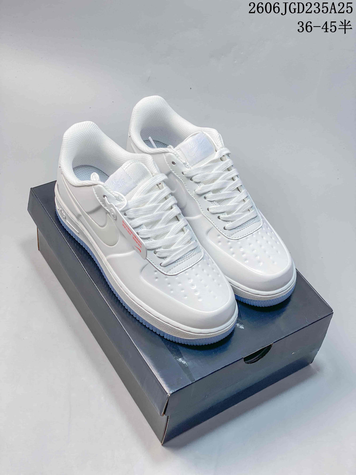 Pair of white low-top lace-up sneakers with perforated toes and side Swoosh details on a dark shoe box