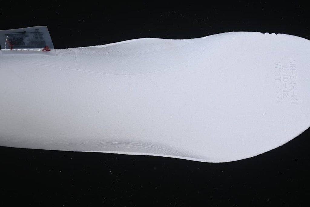 Close-up of a white shoe component with faint embossed markings