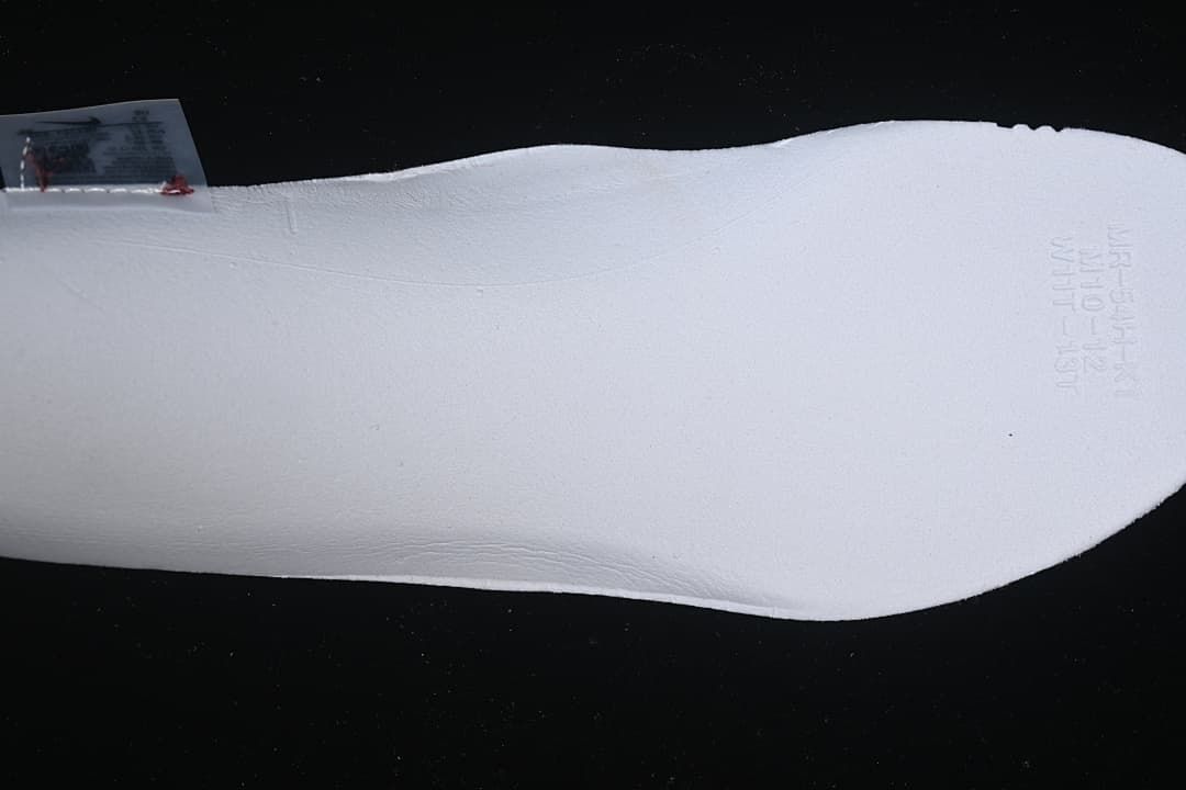 Close-up of a white shoe component with faint embossed markings
